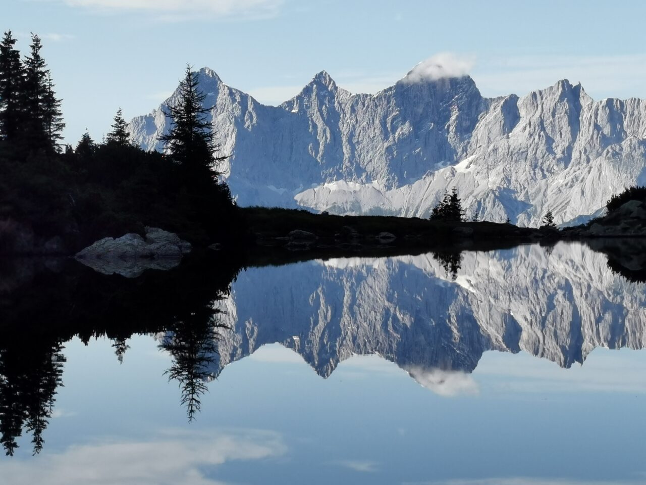 Bei Windstille spiegelt sich das Dachsteinmassiv im Spiegelsee auf der Reiteralm in der Region Schladming-Dachstein